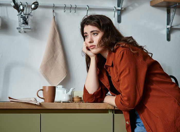 Young woman in the kitchen looking frustrated and refusing to pay after husband burnt steak cooked poorly on the stove.