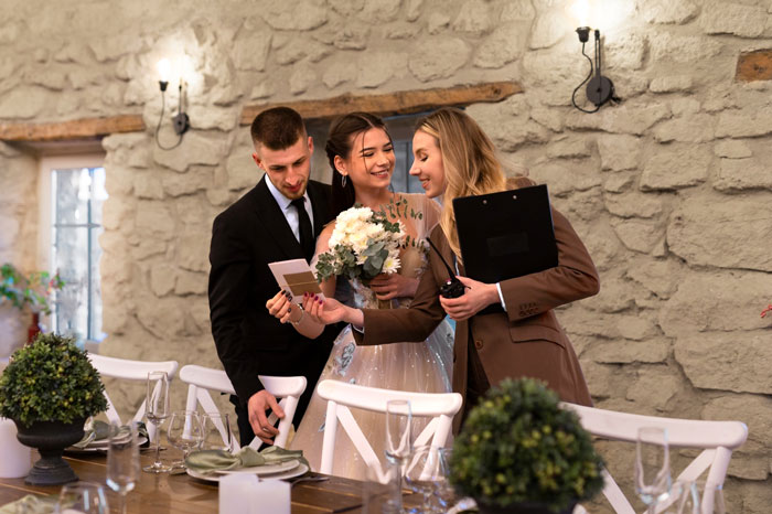 Bride in wedding dress with groom and planner discussing details, highlighting bride refusing MIL's $25K wedding gift debate.