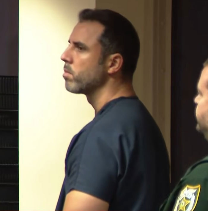 Homem em um tribunal vestindo uma camisa escura, parecendo sério durante um caso envolvendo a morte violenta de uma enfermeira pelas mãos de um homem.