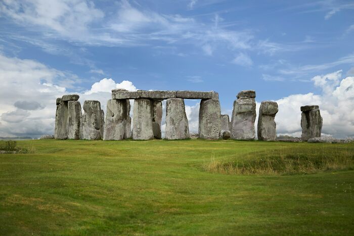 Stonehenge under a blue sky, illustrating popular myths about iconic landmarks around the world in a grassy field.