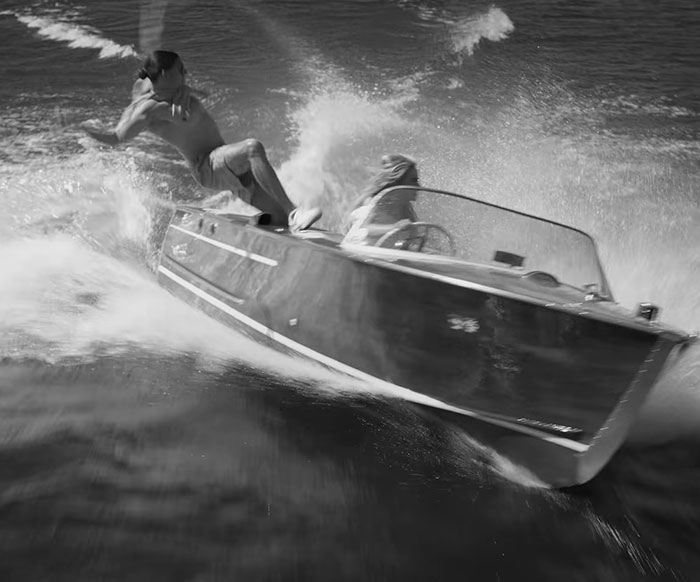 Man falling off speedboat into water with waves splashing, related to Sabrina Carpenter disturbing pattern in music videos.