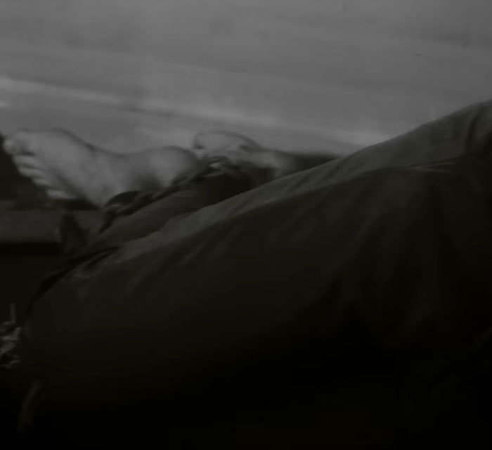 Close-up of a person lying down with bare feet visible, evoking unsettling themes in Sabrina Carpenter music videos.