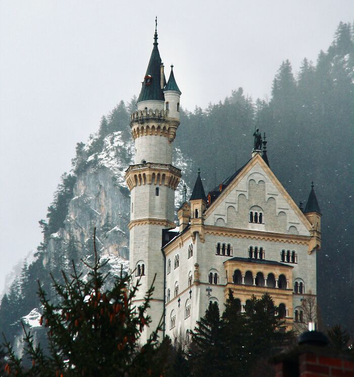 Neuschwanstein Castle surrounded by snowy mountains and trees, illustrating popular myths about iconic landmarks worldwide