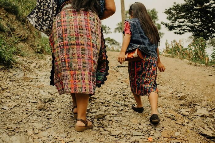 Two girls wearing traditional colorful skirts walking uphill on a rocky path showing culture shock moments for foreigners.