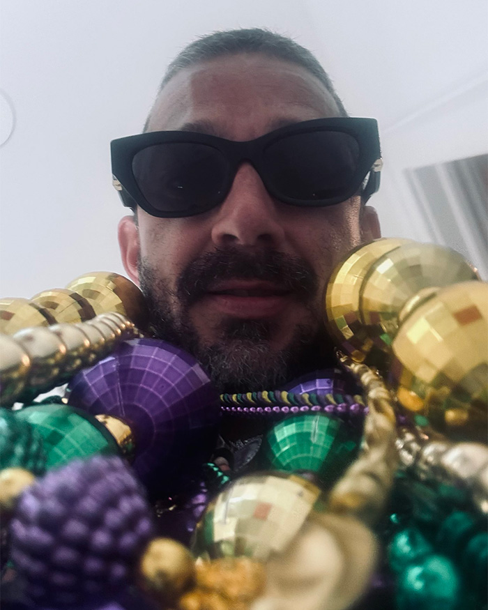 Shia LaBeouf wearing sunglasses and colorful beads, close-up portrait capturing a tense moment in Rome.