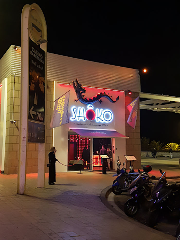 Night view of Sh&ocirc;ko restaurant entrance in Spain with people and motorcycles, linked to suspicious footage in student vanishing case.