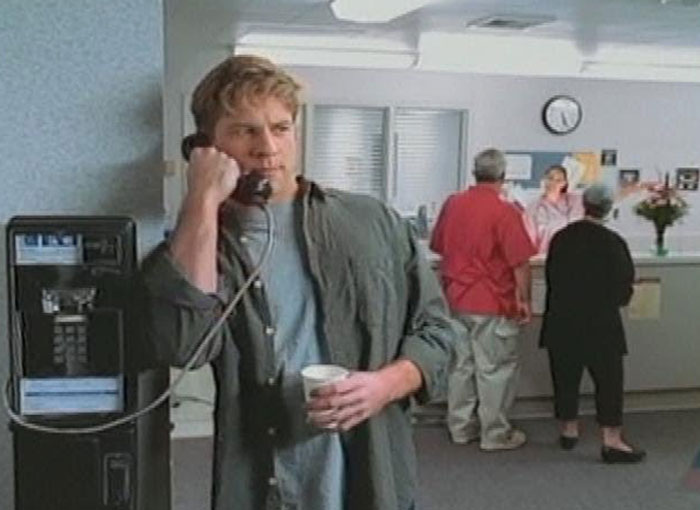 Young man using a payphone in a waiting room, evoking nostalgic childhood memories for many people.