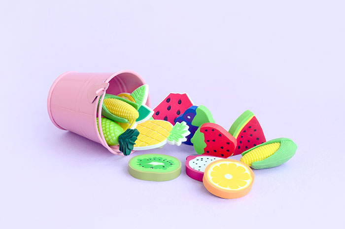 Colorful plastic toy fruits spilling from a pink bucket, evoking childhood memories and nostalgic playtime moments.