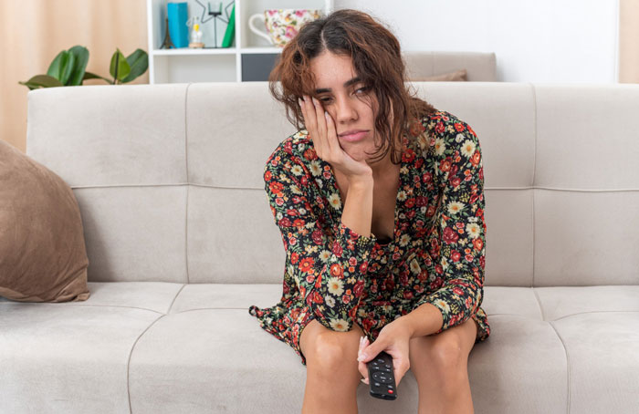 Teen girl looking tired and frustrated on couch, reflecting sacrifice demanded by delusional parents for sixth baby miracle.