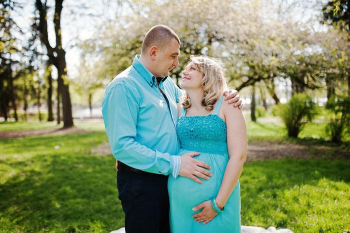 Couple in a park with husband embracing pregnant wife, highlighting parents calling sixth baby a miracle.