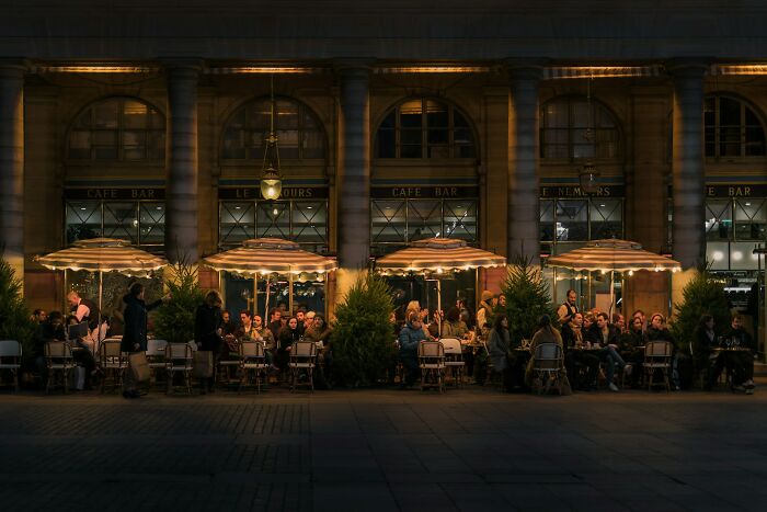 Outdoor café seating at night with people dining and socializing, showcasing cultural things seen in other countries.