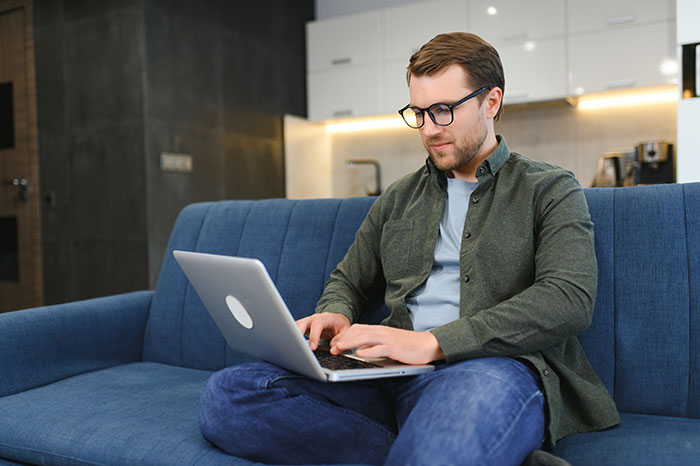 Man on laptop sitting on couch uncovering texts related to obsession with sister's weight in a home setting