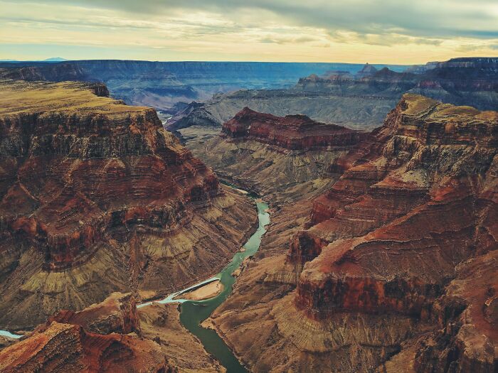 A scenic view of a deep canyon with a winding river, illustrating the contrast of age and timeless natural beauty.