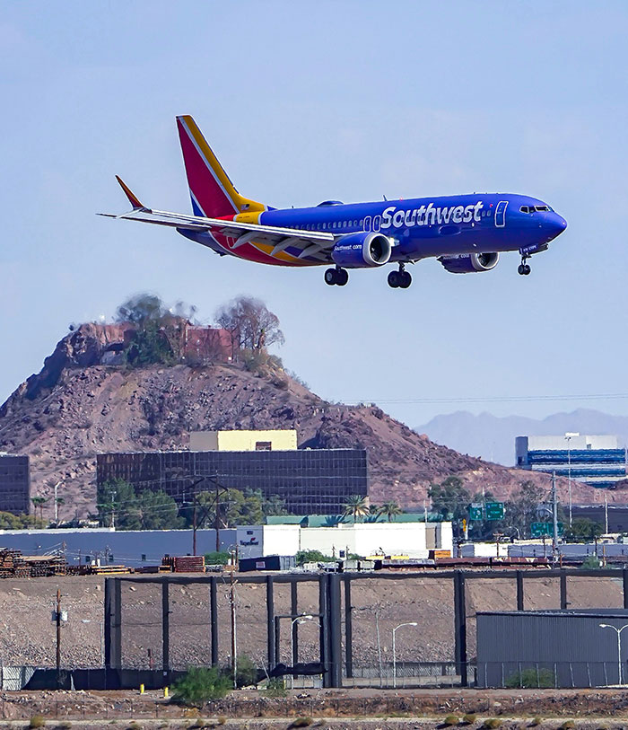 Avião da Southwest Airlines sobrevoando a paisagem da cidade ilustrando a reação da política de tamanho do cliente da companhia aérea.