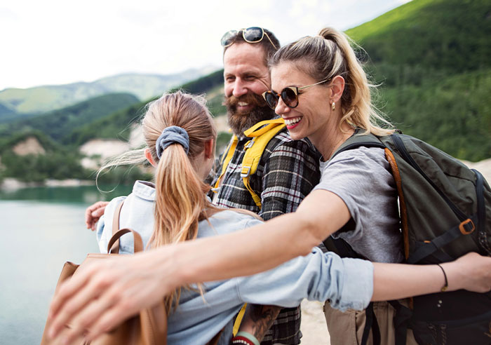 Happy group of friends hugging outdoors by a lake, capturing eye-opening moments of realizing they were truly spoiled.