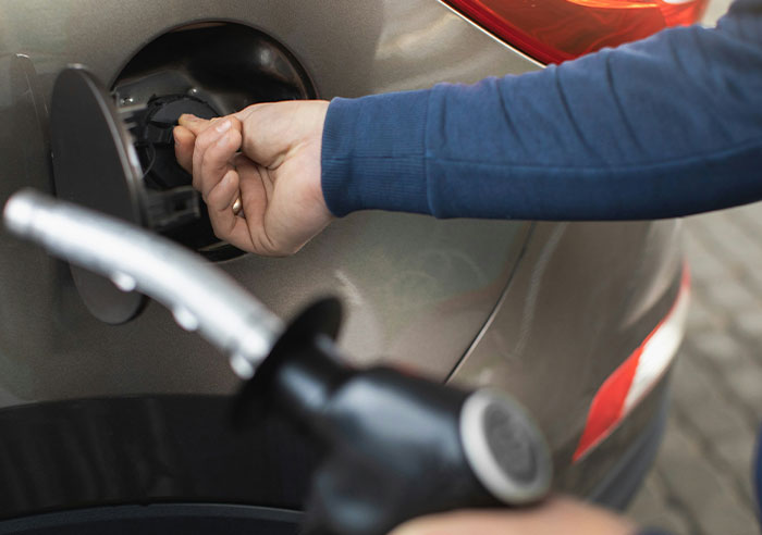 Person unlocking a car fuel cap before filling gas, illustrating a moment of realizing being truly spoiled.