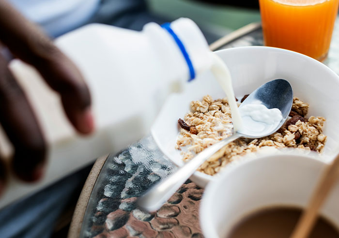 Pouring milk over a bowl of cereal and granola with orange juice and coffee, showing moments of feeling spoiled.
