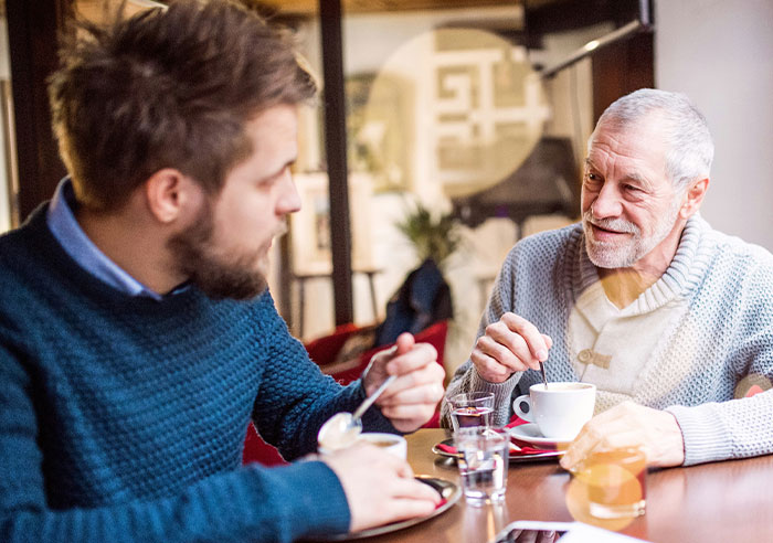 Two men enjoying coffee and conversation in a cozy cafe, illustrating eye-opening moments of being truly spoiled.