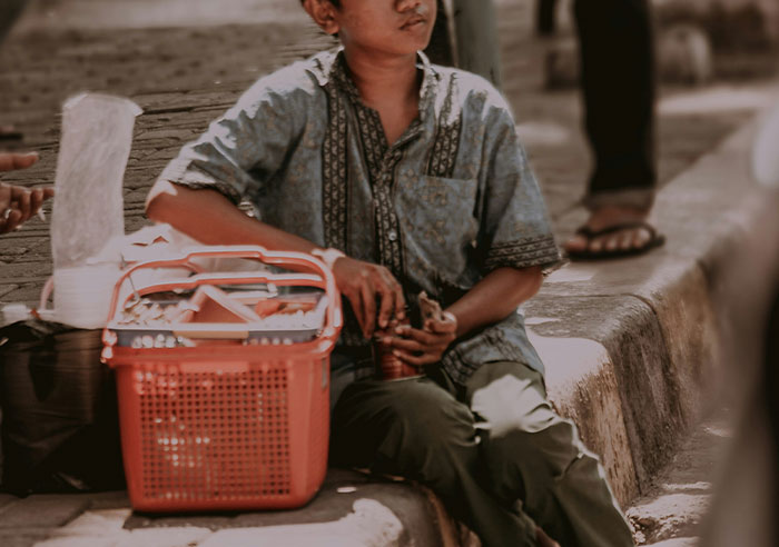 Young boy sitting on a curb with a red basket, capturing a moment that made people realize they were truly spoiled.