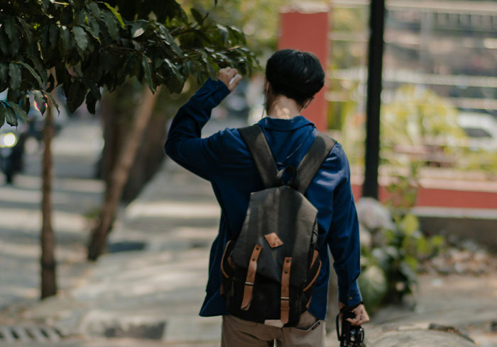 Person with backpack raising fist on tree-lined street, capturing a moment of realization about being truly spoiled.