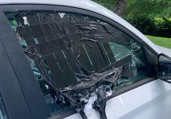 Car window covered with black tape on a white vehicle, showing a moment of being truly spoiled by neglect.