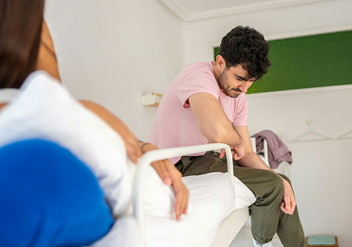 Young man sitting on bed looking thoughtful, capturing an eye-opening moment of realizing he was truly spoiled.