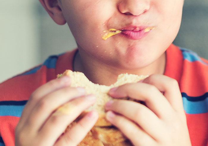 Close-up of a child enjoying a messy sandwich, illustrating moments that made people realize they were truly spoiled.