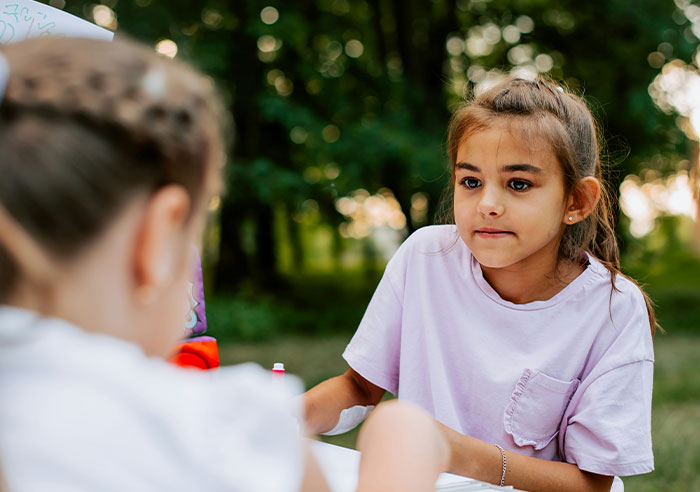 Two young girls outdoors in a park, capturing eye-opening moments of realizing they were truly spoiled.