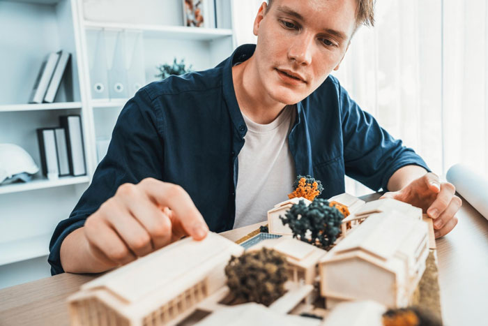 Young man focused on arranging miniature figurines and models, engaged in a detailed DnD game setup at home.