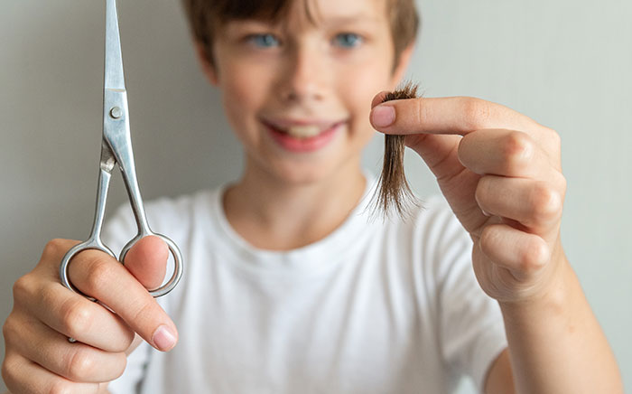 Teen holding scissors and a small cut of hair, symbolizing creepy step-sisters hair cutting incident