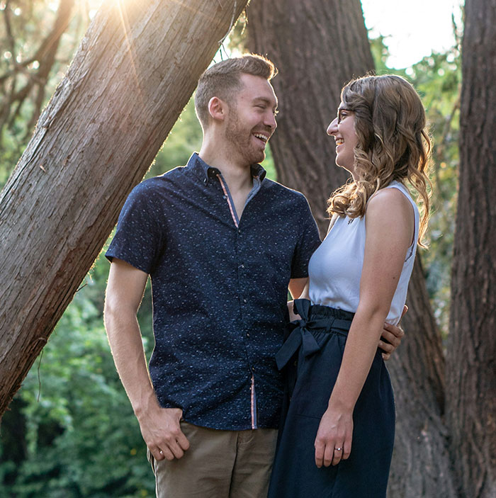 Couple laughing together outdoors showing a woman’s innocent goofy joke revealing a horrible cheating husband.