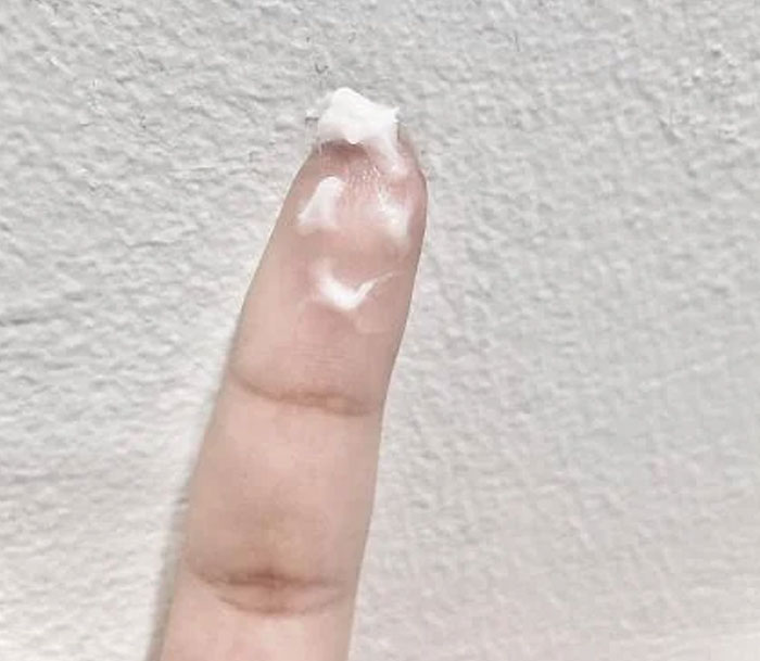 Close-up of a finger with a small amount of cream, illustrating a woman’s innocent goofy joke about her cheating husband.