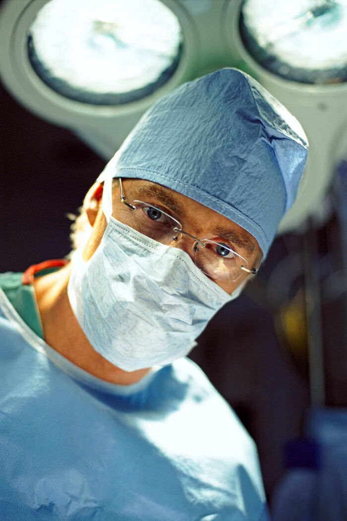 Surgeon in blue scrubs and mask under bright surgical lights, illustrating mind-blowing scientific facts in medicine.