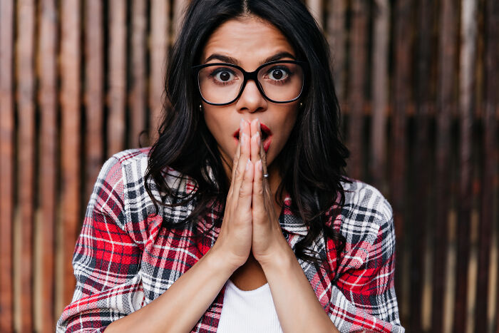Young woman in glasses and plaid shirt showing a surprised reaction illustrating culture shock moments for foreigners