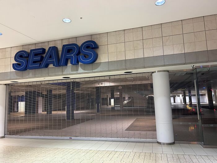 Closed Sears store behind metal gate in a deserted mall, evoking haunting and spine-chilling atmosphere in abandoned places.