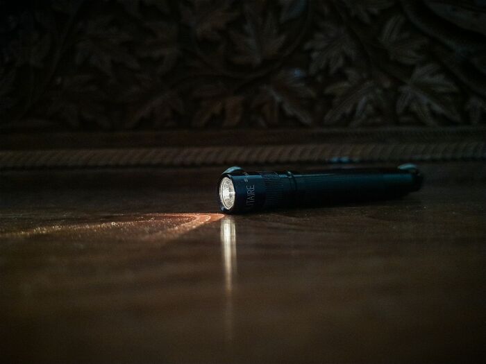 Flashlight casting a dim beam on a wooden floor, evoking eerie urban explorer moments in abandoned spaces.