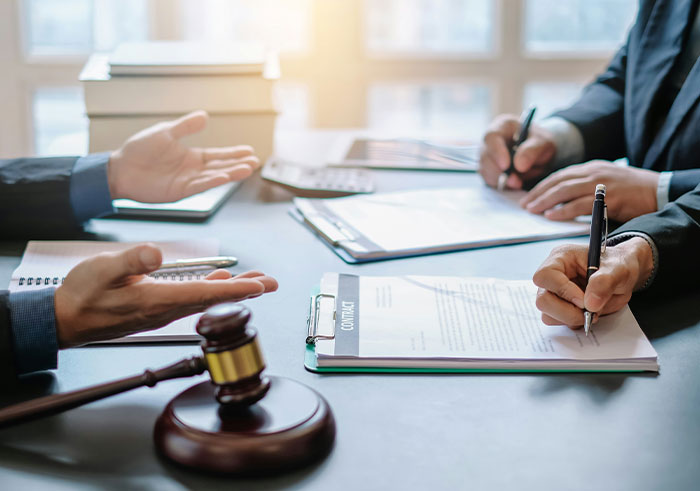 Two men in a legal setting reviewing paternity test documents and signing contracts near a judge's gavel.