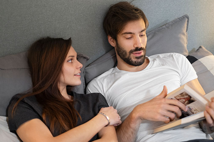 Man and woman lying on a bed, having a deep conversation about things men keep to themselves they want to share.