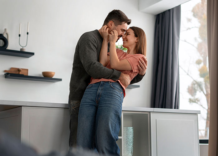 Couple embracing and smiling in a cozy home setting, illustrating things men keep to themselves in relationships.