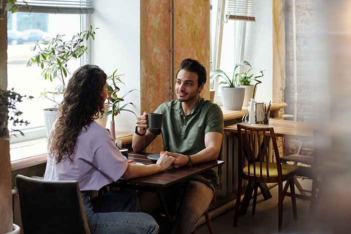 A man and woman having a deep conversation in a cafe, illustrating things men keep to themselves but want to share.