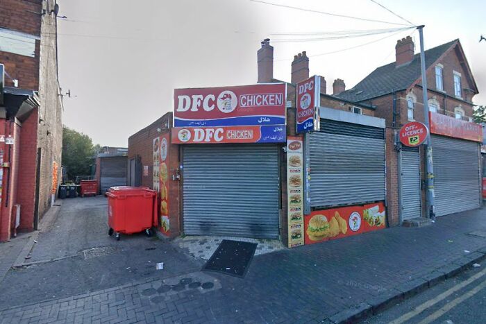 Closed DFC Chicken fast food shop with shutters down on an empty street, reflecting disturbing real life scenes.