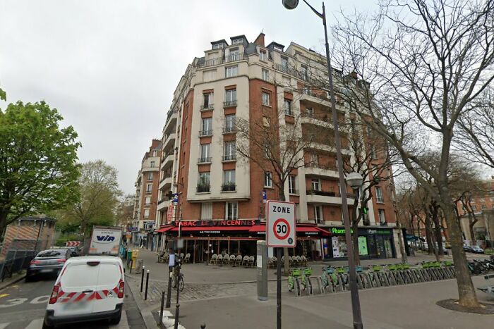 Urban street corner with parked vehicles and bicycles, depicting a disturbing scene from real life nightmares.