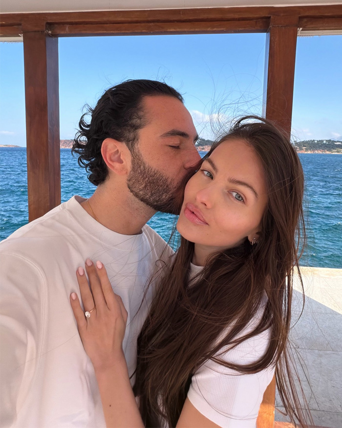 Couple by the sea with woman showing engagement ring, celebrating romantic proposal of most beautiful girl in the world.
