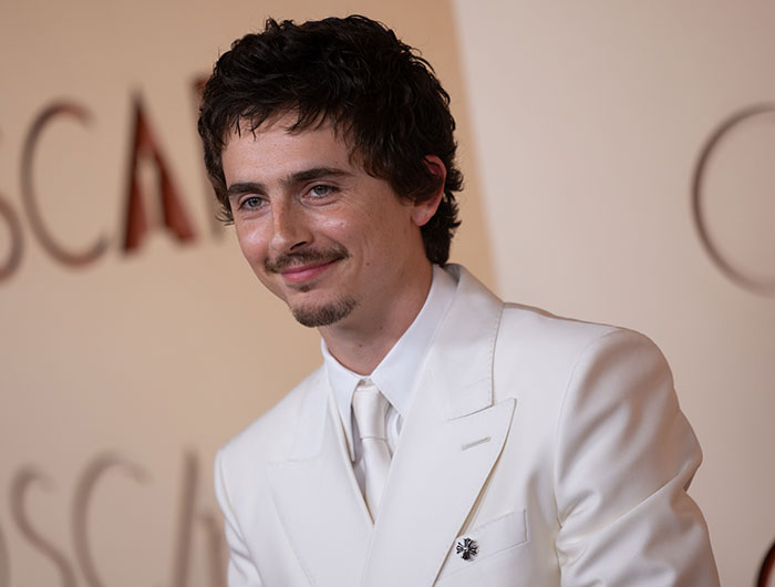 Timoth&eacute;e Chalamet in a white suit at a formal event, related to ballet drama and Sydney Sweeney ballerina pics.