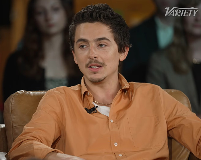 Timoth&eacute;e Chalamet in casual orange shirt during interview, sparking hilarious meme amid opera and ballet backlash.