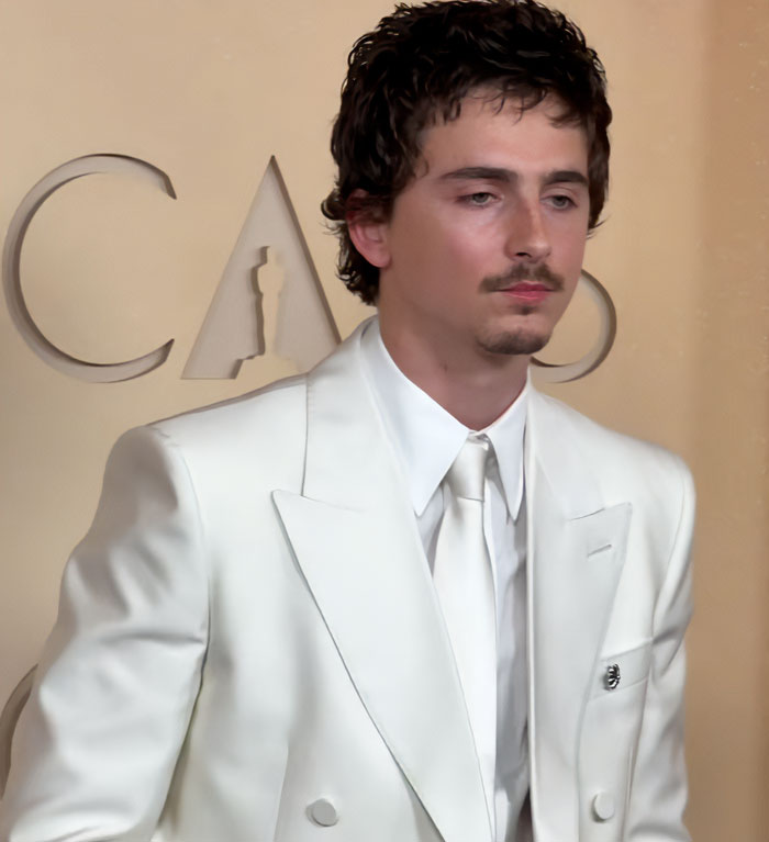 Timothée Chalamet no Oscar 2026, vestido com um terno branco, enquanto especialista em linguagem corporal percebe interação com Kylie Jenner. Timothée Chalamet no Oscar 2026, vestido com um terno branco, enquanto especialista em linguagem corporal percebe interação com Kylie Jenner.