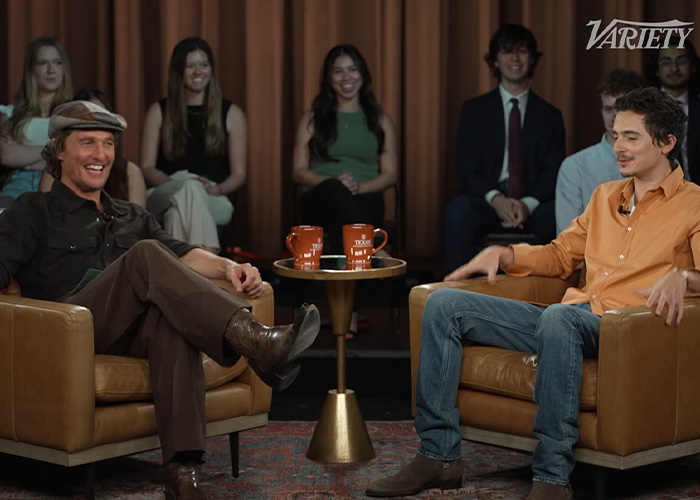 Steven Spielberg and Timoth&eacute;e Chalamet seated in armchairs during an interview with audience in the background.
