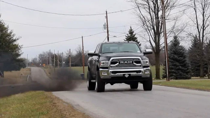 Black RAM pickup truck driving on a rural road emitting thick black smoke, illustrating environmental impact and adulthood milestones.