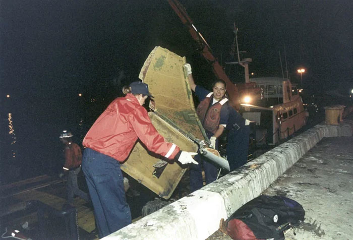 Two people lifting a large object near a dock at night illustrating humans neurologically entering adulthood at age 32.