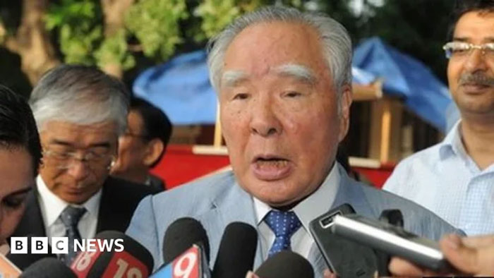 Elderly man speaking to multiple reporters with microphones, illustrating adults and neurological development concepts.